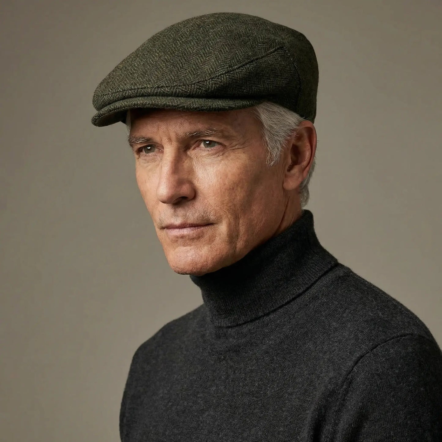 Ældre mand iført mørkegrøn tweed flat cap i herringbone-mønster og mørk rullekravesweater – kasketmand.dk