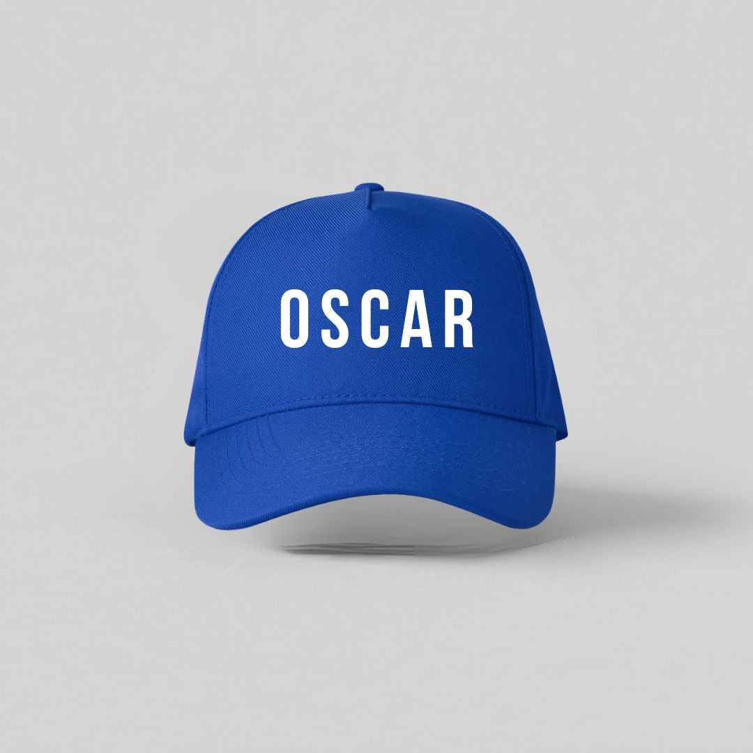 Blå børnekasket med hvidt navnetryk Oscar set forfra