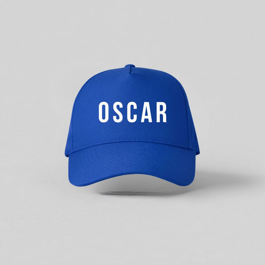 Blå børnekasket med hvidt navnetryk Oscar set forfra